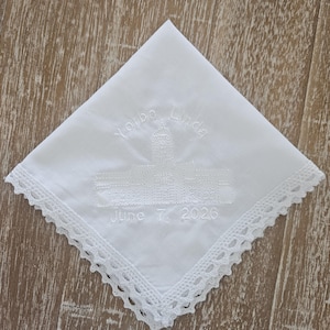 Pode incluir: Lenço branco com bordado "Yorba Linda" e "June 7, 2026". O lenço tem uma borda de renda decorativa. O bordado apresenta um desenho de edifício.