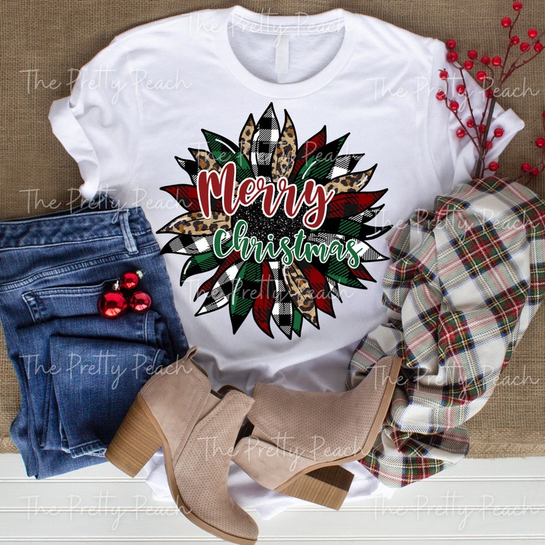 May include: White t-shirt with a red, green, black, and white plaid sunflower design. The sunflower has a leopard print center and the words "Merry Christmas" are written in the center.