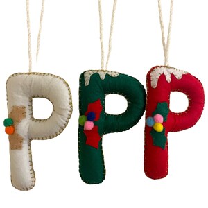 May include: Three felt Christmas decorations shaped like the letter P. The ornaments are decorated with different colours and patterns, including white, green, red, gold, and multi-coloured pom-poms.