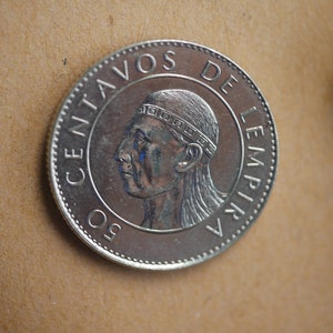 May include: A silver coin with the inscription "50 CENTAVOS DE LEMPIRAS" and a portrait of a person with a headdress.