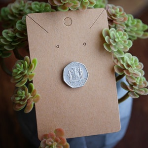 May include: A brown paper earring display card with a hole in the top and two holes on the bottom. A silver Jamaican one dollar coin is on the card.