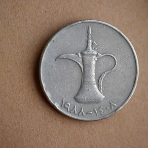 May include: A silver coin with a traditional Arabic coffee pot design. The coin has the text "1971-1391" on the bottom.
