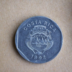 May include: A silver Costa Rican coin with the country's coat of arms and the year 1992.