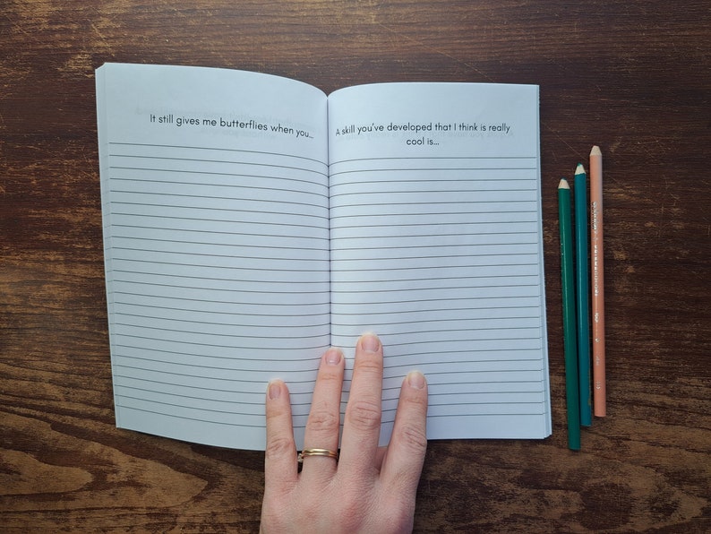Puede incluir: Un cuaderno abierto con p&aacute;ginas rayadas. La p&aacute;gina izquierda tiene el texto "It still gives me butterflies when you..." y la p&aacute;gina derecha tiene el texto "A skill you've developed that I think is really cool is..."