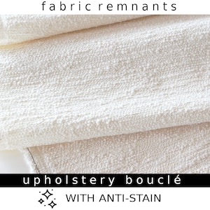 May include: White upholstery fabric remnant with a boucle texture. The fabric is labelled "upholstery boucle with anti-stain."