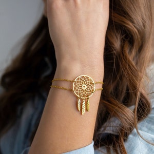 May include: A gold-toned bracelet with a delicate dreamcatcher charm and dangling feathers.