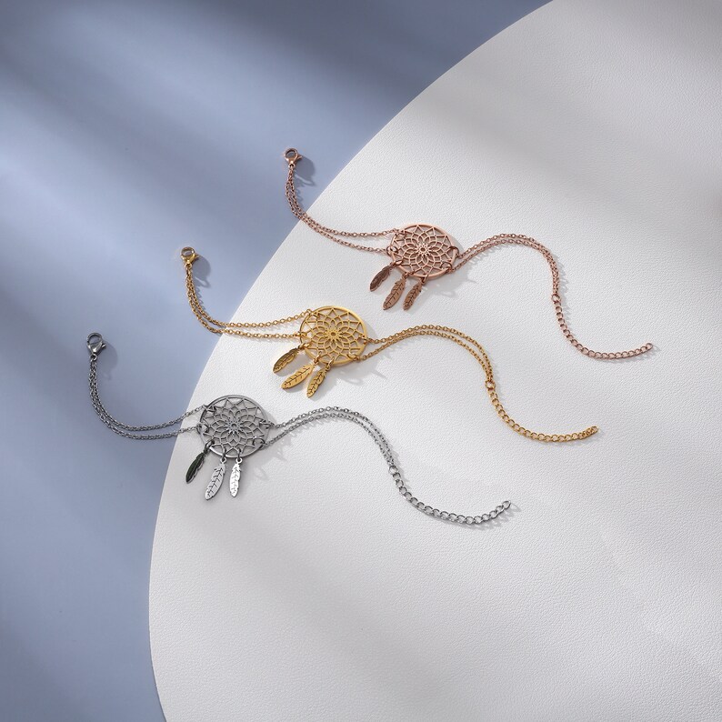 May include: Three silver chain bracelets with a dreamcatcher pendant. Each pendant features a circular design with a web-like pattern and feathers.