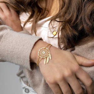 May include: A gold-toned bracelet with a dreamcatcher charm and three dangling feathers.