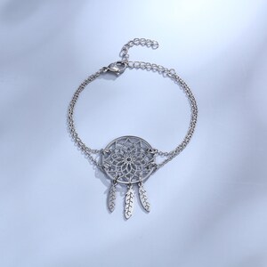 May include: A silver bracelet with a dreamcatcher charm and three feathers. The bracelet is made of two chains.