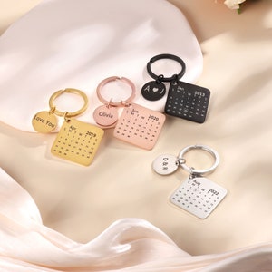 Peut inclure: Quatre porte-clés en or, argent et noir avec des dates de calendrier gravées et des messages personnalisés. Les porte-clés comportent un charme rond avec un cœur et les initiales "A J", "Olivia", "Love You" et "D&R".