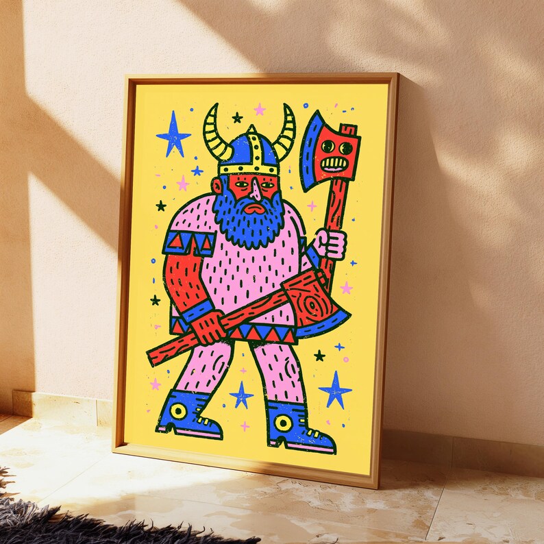 K&ouml;nnte beinhalten: Ein gerahmter Kunstdruck auf gelbem Hintergrund mit einem Cartoon-Wikinger mit blauem Bart und geh&ouml;rntem Helm. Die Figur h&auml;lt eine rote Axt mit einem Gesicht auf der Klinge. Das Design enth&auml;lt blaue und rosa Sterne, die um die Figur verteilt sind.