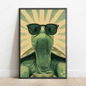 May include: A framed wall art print featuring a green turtle wearing black sunglasses. The turtle is centered against a background of radiating light beige and green dotted sunburst lines. The illustration has a detailed texture on the skin.