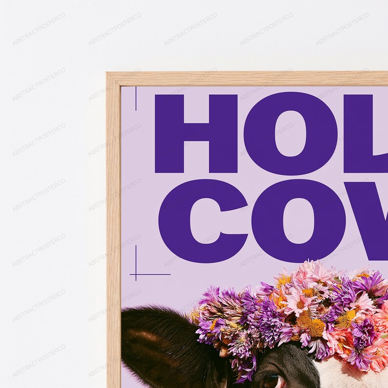 May include: A framed wall art print featuring a black and white cow wearing a vibrant floral crown of purple, pink, and yellow flowers. The background is a light lavender color with the bold purple text HOLY COW printed at the top.