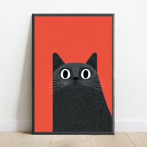 May include: A rectangular framed wall art print featuring a stylized illustration of a black cat with large white eyes and thin white whiskers. The cat is positioned against a solid, vibrant orange background, enclosed in a thin black frame.