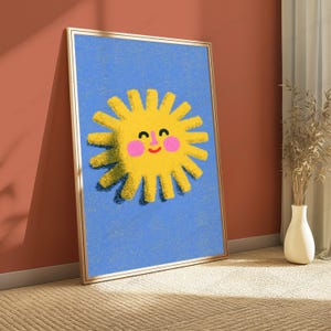 May include: A framed vertical wall art print featuring a bright yellow sun with a smiling face, pink cheeks, and a textured appearance set against a solid blue background. The sun has numerous rays extending outward and a dark shadow effect.