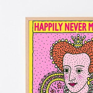 May include: A framed wall art print featuring a stylized illustration of a queen with orange hair and a crown. The background is pink with black dots, and the text at the top reads HAPPILY NEVER M in bright pink letters on a yellow border.
