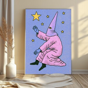 May include: A framed wall art print featuring a stylized illustration of a figure in a pink hooded robe with a single yellow eye, reaching toward a large yellow star against a textured light blue background filled with smaller yellow stars.