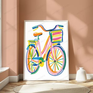 May include: A framed art print featuring a colorful, abstract illustration of a bicycle. The bicycle is rendered with bold, expressive brushstrokes in shades of pink, orange, yellow, blue, and green, and includes a front basket with striped details.