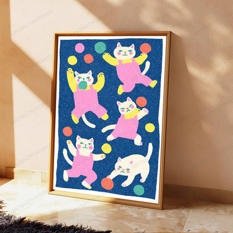 K&ouml;nnte beinhalten: Ein gerahmter Wandkunstdruck mit f&uuml;nf wei&szlig;en Katzen in rosa Latzhosen vor einem dunkelblauen, texturierten Hintergrund. Die Katzen sind in verschiedenen verspielten Posen dargestellt, umgeben von verstreuten bunten Kreisen in Gelb, Orange, Pink und Gr&uuml;n.