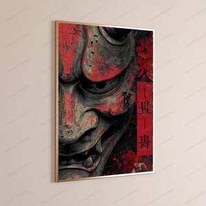 K&ouml;nnte beinhalten: Ein rechteckiger Wandkunstdruck mit einer Nahaufnahme einer japanischen Hannya-Maske in Grau- und Schwarzt&ouml;nen mit kr&auml;ftigen roten Spritzern. Ein vertikales rotes rechteckiges Feld auf der rechten Seite enth&auml;lt schwarze japanische Kanji-Zeichen.