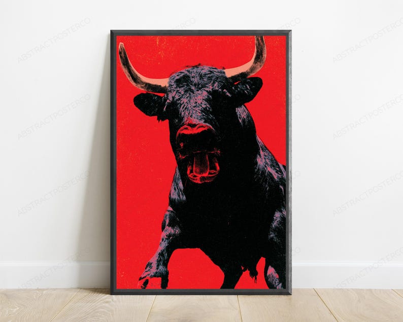 K&ouml;nnte beinhalten: Ein gerahmter vertikaler Wandkunstdruck mit einer kontrastreichen Illustration eines schwarzen Stiers mit hellen H&ouml;rnern vor einem einfarbigen, leuchtend roten Hintergrund. Der Stier ist in einer frontalen Haltung mit offenem Maul dargestellt.