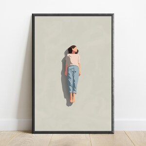 Pu&ograve; includere: Una stampa artistica da parete incorniciata con un'illustrazione minimalista di una persona dai capelli scuri sdraiata su uno sfondo beige chiaro. La persona indossa una maglietta rosa chiaro a maniche corte e pantaloni azzurri, proiettando un'ombra.