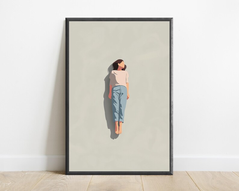 Pu&ograve; includere: Una stampa artistica da parete incorniciata con un'illustrazione minimalista di una persona dai capelli scuri sdraiata su uno sfondo beige chiaro. La persona indossa una maglietta rosa chiaro a maniche corte e pantaloni azzurri, proiettando un'ombra.