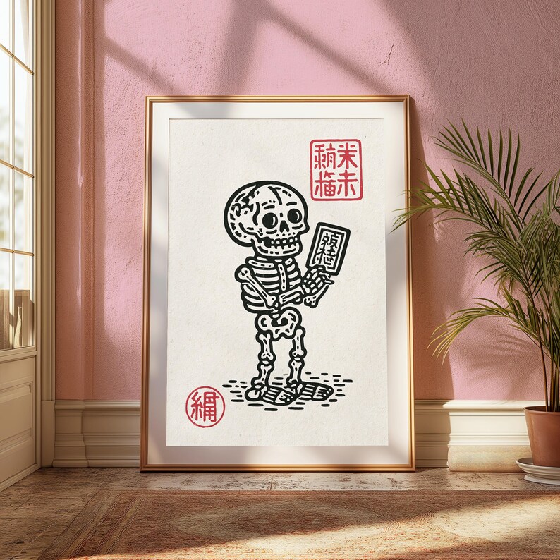 May include: A framed wall art print featuring a black line drawing of a skeleton holding a small rectangular tablet. The artwork includes red square stamps with Asian characters in the top right and bottom left corners on a cream background.