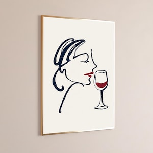 May include: A framed wall art print featuring a minimalist line drawing of a profile of a face in dark blue ink. The figure has red lips and is positioned next to a wine glass filled with red liquid, rendered in the same dark blue and red color palette.