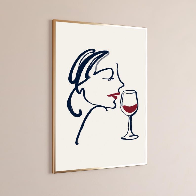 May include: A framed wall art print featuring a minimalist line drawing of a profile of a face in dark blue ink. The figure has red lips and is positioned next to a wine glass filled with red liquid, rendered in the same dark blue and red color palette.