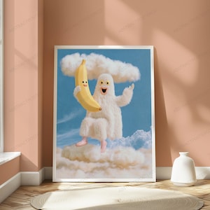 K&ouml;nnte beinhalten: Ein gerahmter Wandkunstdruck mit einer surrealen Illustration eines wei&szlig;en, pelzigen, geisterhaften Wesens mit einem breiten, l&auml;chelnden Gesicht. Das Wesen schwebt in einem blauen Himmel zwischen wei&szlig;en Wolken und h&auml;lt eine gro&szlig;e, gelbe, l&auml;chelnde Banane.