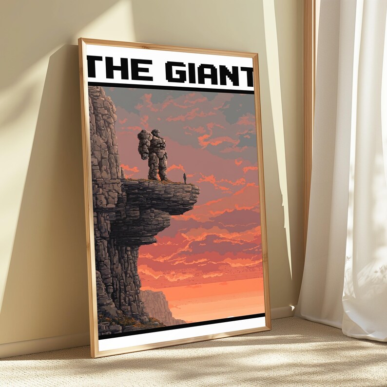 May include: A framed rectangular wall art print featuring pixel art of a large stone figure standing on a cliff edge at sunset. The text THE GIANT is printed in bold black block letters at the top. The scene depicts a rocky landscape with orange and pink clouds in the sky.