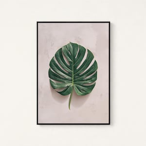 May include: A framed wall art print featuring a single, large, dark green monstera leaf with characteristic splits and holes, centered against a light, textured, off-white background. The artwork is enclosed in a thin, black rectangular frame.