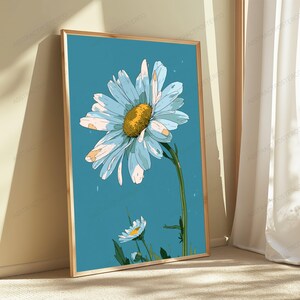 May include: A framed vertical wall art print featuring a large daisy with light blue and white petals and a textured yellow center, set against a solid teal background. A smaller daisy bud is positioned below the main flower on a green stem.