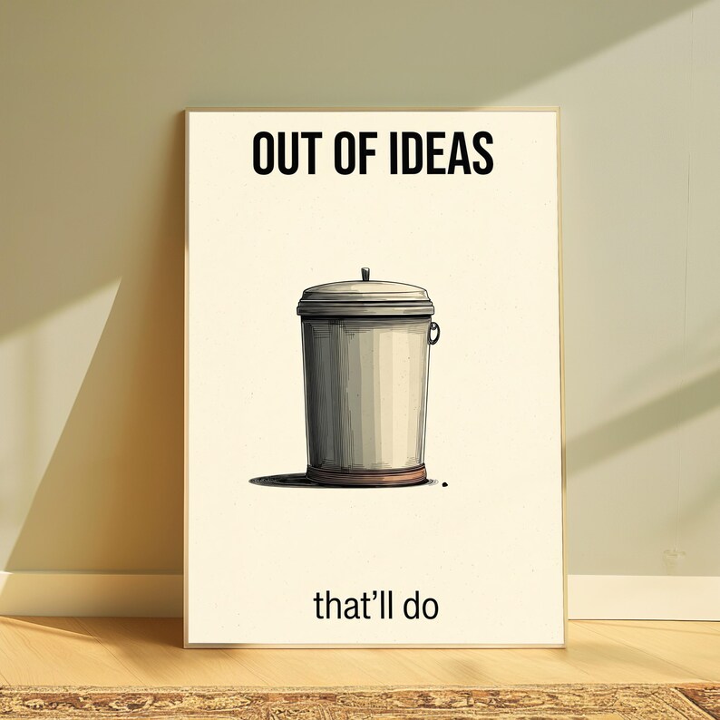 K&ouml;nnte beinhalten: Ein rechteckiger Wandkunstdruck auf cremefarbenem Hintergrund mit einer zentrierten Illustration eines grauen Metallm&uuml;lleimers mit Deckel. Der Text "OUT OF IDEAS" ist oben schwarz gedruckt, der Text "that'll do" unten schwarz gedruckt.