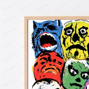 May include: A framed wall art print featuring a stack of stylized, colorful faces in a comic book style. The top left is a blue wolf-like creature, top right is a yellow cracked skull, middle is a red face, and bottom right is a green face.