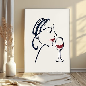May include: A framed wall art print featuring a continuous dark blue line drawing of a profile of a face with red lips, positioned next to a dark blue line drawing of a wine glass filled with red liquid, set against a plain white background.