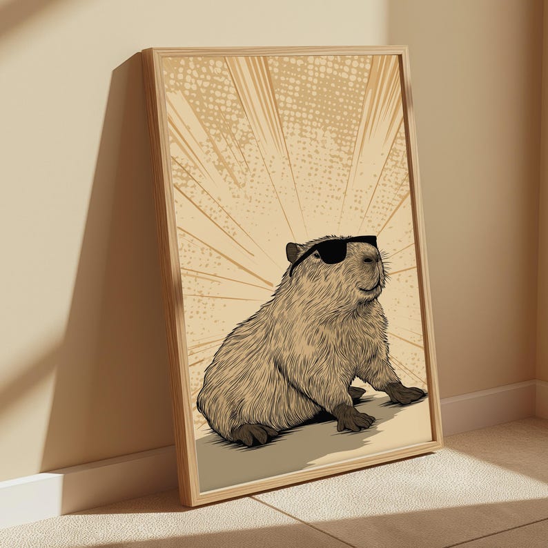 May include: A framed wall art print featuring a detailed illustration of a capybara wearing black sunglasses. The capybara is rendered in shades of brown and tan, set against a light beige background with radiating lines and a subtle dot pattern.