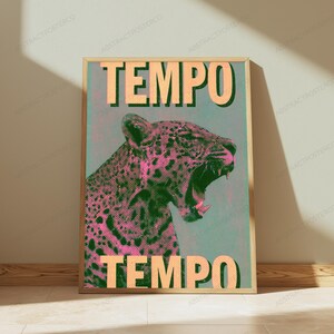 May include: A rectangular wall art print in a light wood frame featuring a stylized leopard with an open mouth. The leopard is rendered in pink and black halftone dots against a teal background. The word TEMPO appears in large beige letters.