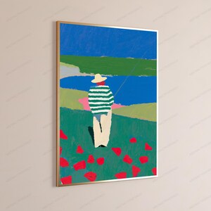 Op de afbeelding: Een ingelijste verticale kunstdruk met een gestileerd schilderij van een persoon met een strooien hoed en een groen-wit gestreept shirt met een lichte broek, staand in een groen veld met rode bloemen uitkijkend over een blauw wateroppervlak.