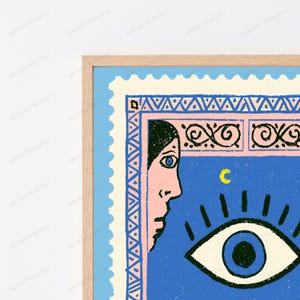 May include: A framed wall art print featuring a stylized postage stamp design. The illustration shows a profile of a face in pink, a large blue eye, and a yellow crescent moon on a blue background, bordered by pink and blue geometric patterns.