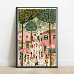May include: A framed art print depicting a cobblestone street scene with pink buildings, tall green trees, and people walking under pink and white striped umbrellas. The illustration features a warm colour palette with soft textures and detailed foliage.