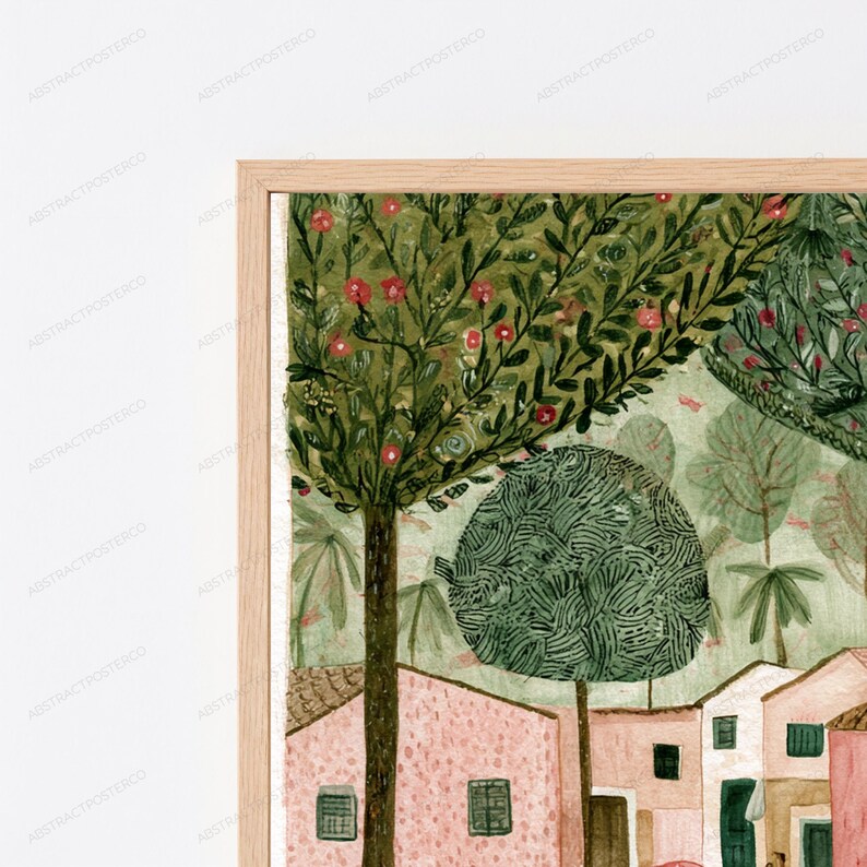 May include: A framed wall art print featuring a landscape illustration of pink buildings nestled among green trees with red blossoms. The artwork displays a stylized town scene with textured foliage and architectural details in a light wood frame.