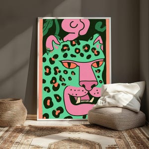 May include: A framed rectangular wall art print featuring a stylized illustration of a leopard with a mint green coat, pink face, and orange eyes. The leopard has black spots and is set against a dark green background with a pink border.