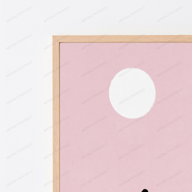 May include: A framed wall art print featuring a solid light pink background with a large white circle positioned in the upper right quadrant. The frame is constructed from light-toned wood with a visible grain, surrounding the rectangular print.