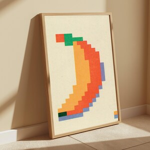 K&ouml;nnte beinhalten: Ein gerahmter Wandkunstdruck mit einer verpixelten Bananengrafik. Die Banane besteht aus orangefarbenen, roten und blauen quadratischen Bl&ouml;cken auf cremefarbenem Hintergrund. Ein kleiner gr&uuml;ner Block stellt den Stiel dar, umrahmt von hellem Holz.