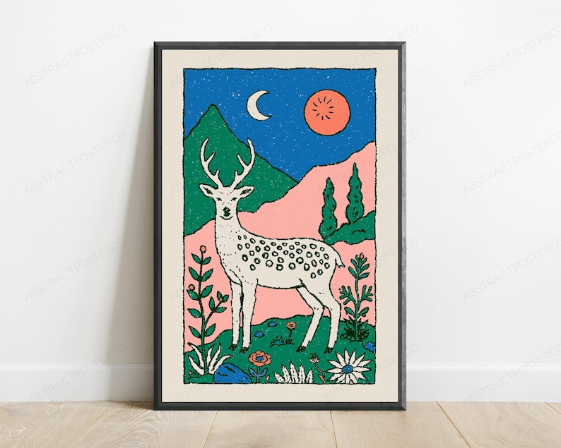 May include: A framed art print featuring a white spotted deer standing in a field of flowers. The background displays green mountains, a blue starry sky with a crescent moon, and a round orange sun. The illustration uses bold lines and colors.