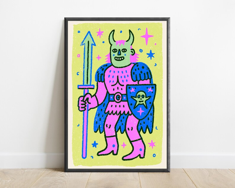 May include: A framed art print featuring a stylized illustration of a horned figure in pink armor, holding a blue sword and a blue shield with a skull emblem. The character has a light green face and is set against a bright lime green background.