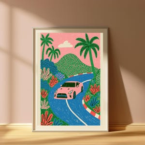 May include: A framed art print featuring a pink sports car driving along a winding blue road. The scene includes green hills, palm trees, and red and white striped curbing against a pink sky with a single white cloud, rendered in a textured style.