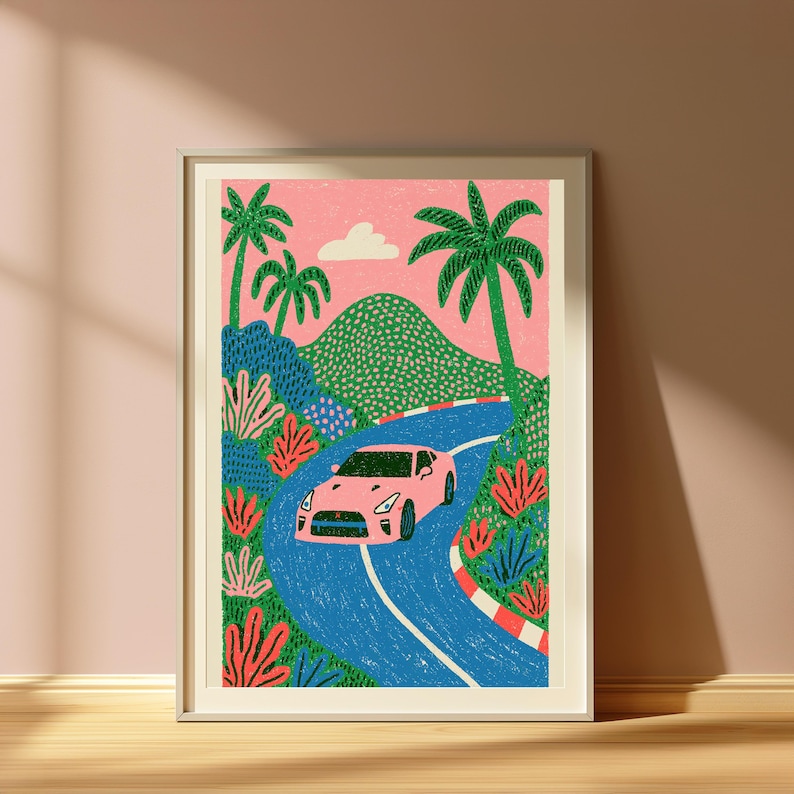 May include: A framed art print featuring a pink sports car driving along a winding blue road. The scene includes green hills, palm trees, and red and white striped curbing against a pink sky with a single white cloud, rendered in a textured style.